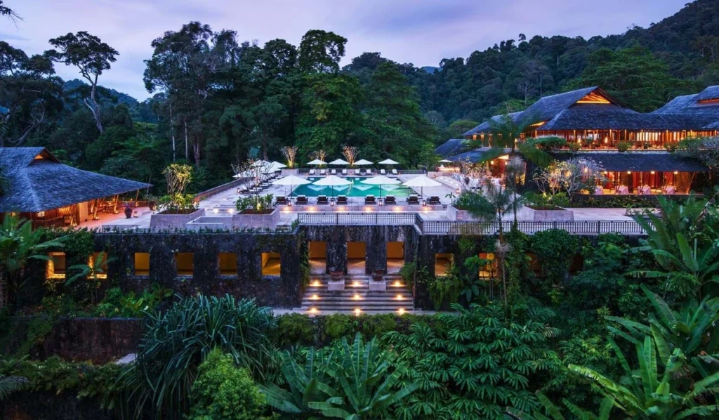 Aerial view of a luxury eco-resort nestled in lush tropical rainforest, showcasing sustainable architecture integrated with nature—an example of harmony between development and biodiversity.
